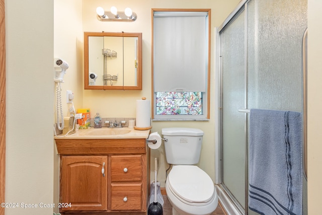 bathroom with walk in shower, vanity, and toilet