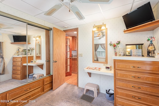 interior space featuring a paneled ceiling, ceiling fan, and a closet