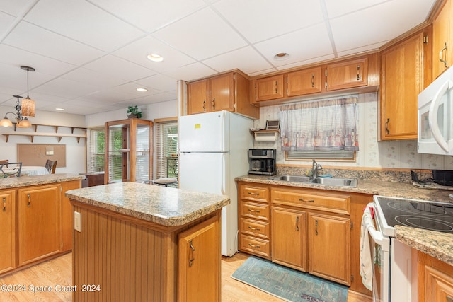 kitchen featuring white appliances, a kitchen island, light wood-type flooring, a drop ceiling, and sink