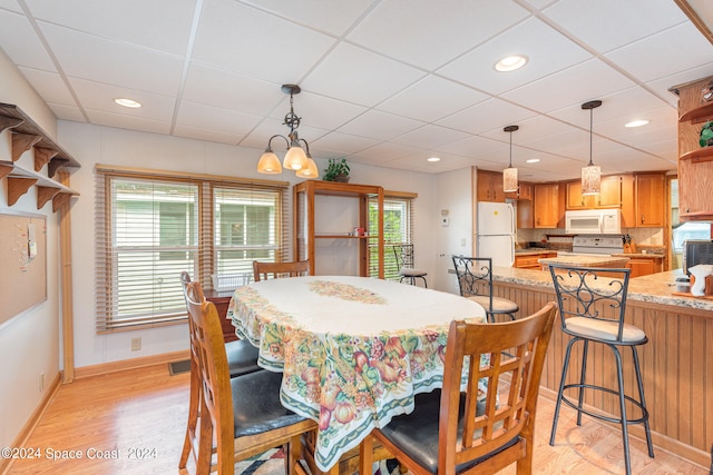 dining room featuring light hardwood / wood-style flooring and a drop ceiling