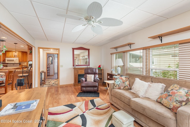 living room featuring ceiling fan, a paneled ceiling, and hardwood / wood-style floors