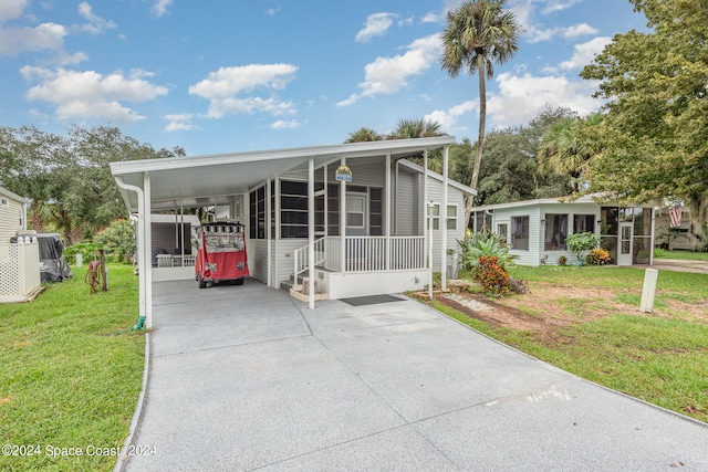 manufactured / mobile home with a sunroom, a front lawn, and a carport