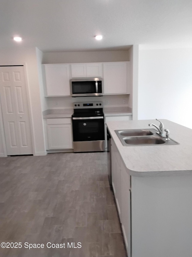 kitchen featuring an island with sink, appliances with stainless steel finishes, sink, and white cabinets