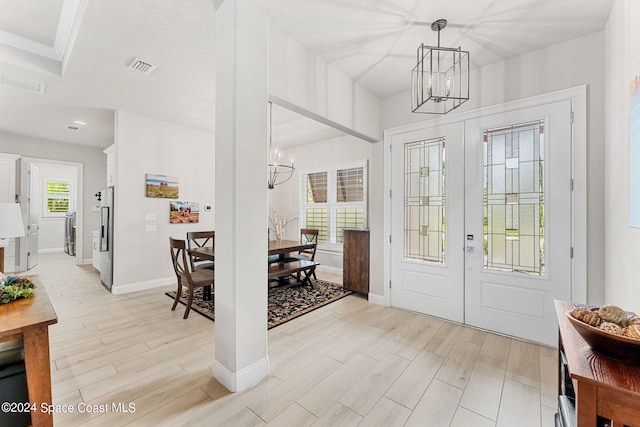 foyer featuring light hardwood / wood-style floors, french doors, a textured ceiling, and a chandelier