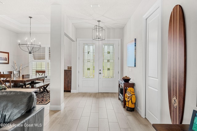 entrance foyer with a chandelier, a textured ceiling, and light hardwood / wood-style floors