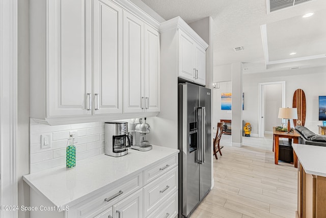 kitchen with high quality fridge, white cabinetry, light hardwood / wood-style flooring, and a textured ceiling