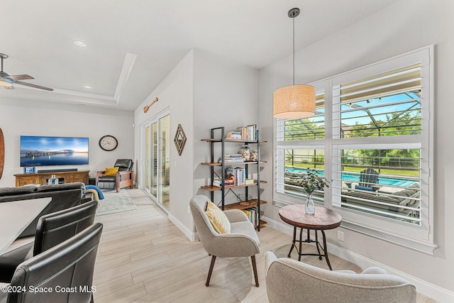 interior space featuring ceiling fan, a raised ceiling, and light hardwood / wood-style flooring