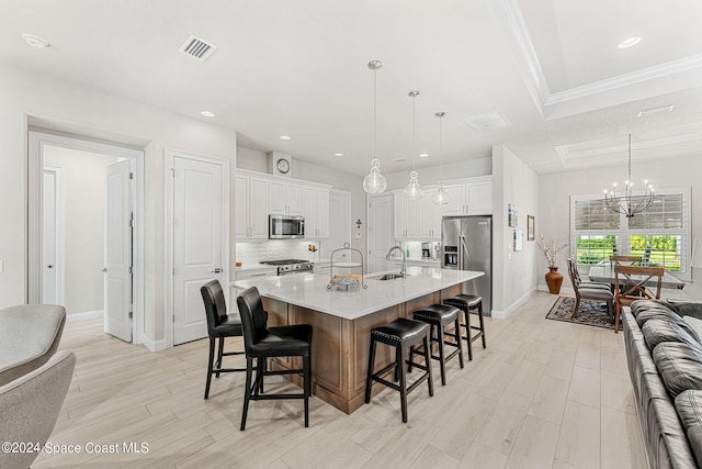 kitchen featuring white cabinets, a breakfast bar area, appliances with stainless steel finishes, a spacious island, and pendant lighting