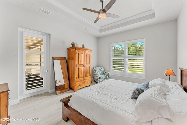 bedroom featuring ceiling fan, a raised ceiling, light wood-type flooring, and crown molding