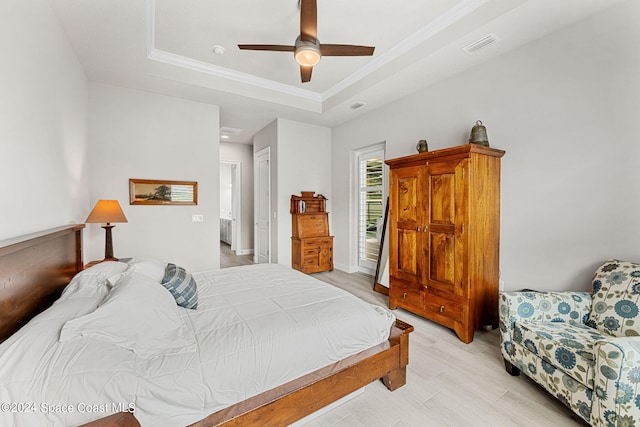 bedroom featuring a closet, a raised ceiling, light wood-type flooring, and ceiling fan