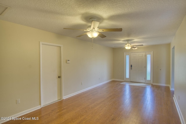 empty room with ceiling fan, a textured ceiling, and light wood-type flooring