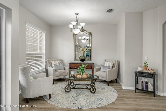 sitting room featuring hardwood / wood-style flooring, a notable chandelier, and a textured ceiling