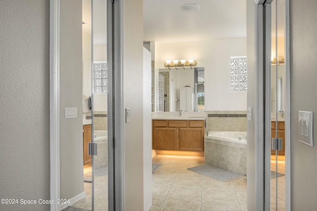 bathroom with a relaxing tiled tub, tile patterned flooring, vanity, and a textured ceiling