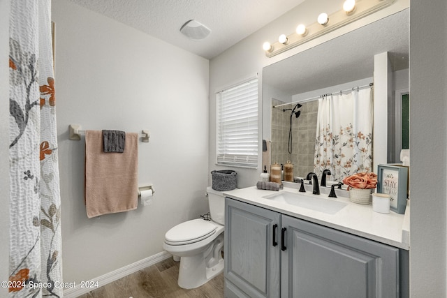 bathroom featuring toilet, wood-type flooring, a shower with curtain, vanity, and a textured ceiling