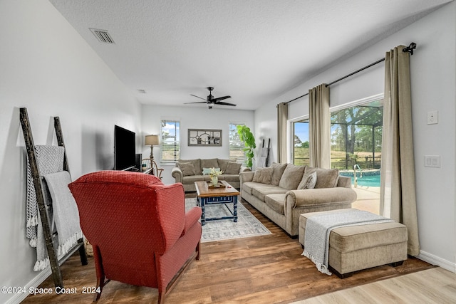 living room with hardwood / wood-style flooring, ceiling fan, and a textured ceiling