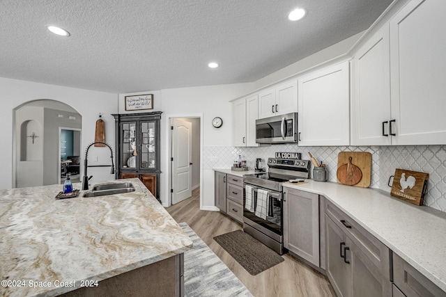 kitchen featuring light hardwood / wood-style floors, sink, light stone counters, stainless steel appliances, and white cabinets