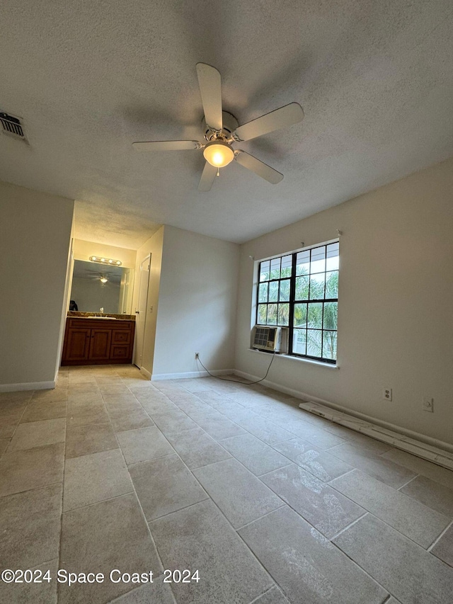 interior space with cooling unit, ceiling fan, and a textured ceiling