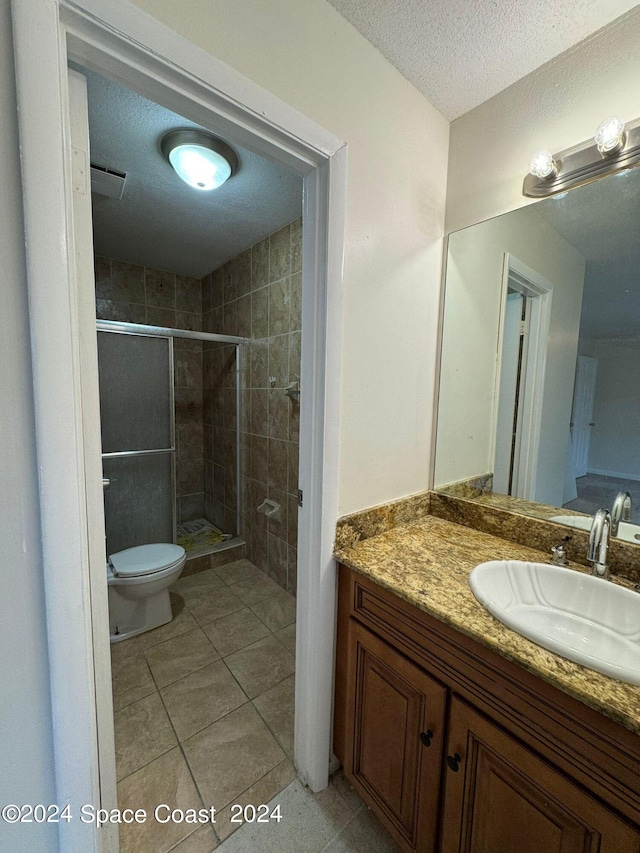 bathroom featuring an enclosed shower, vanity, tile patterned flooring, and toilet