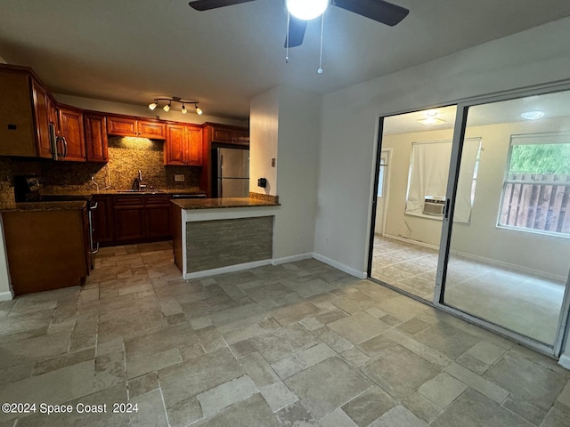 kitchen featuring ceiling fan, kitchen peninsula, sink, tasteful backsplash, and stainless steel appliances