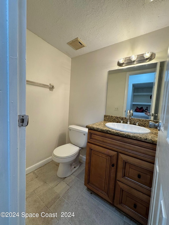 bathroom featuring vanity, toilet, and a textured ceiling