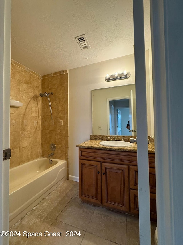 full bathroom featuring tiled shower / bath, vanity, toilet, and a textured ceiling