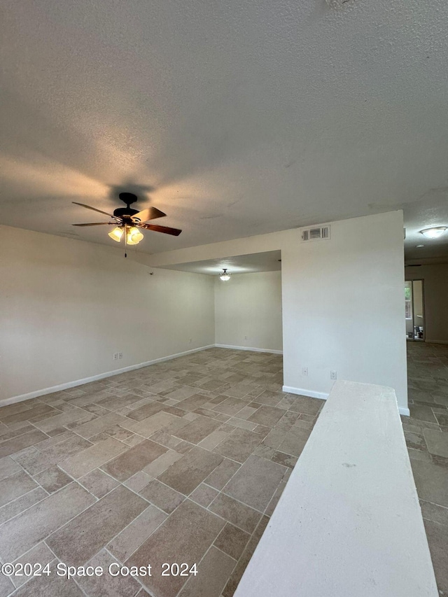 empty room with ceiling fan and a textured ceiling