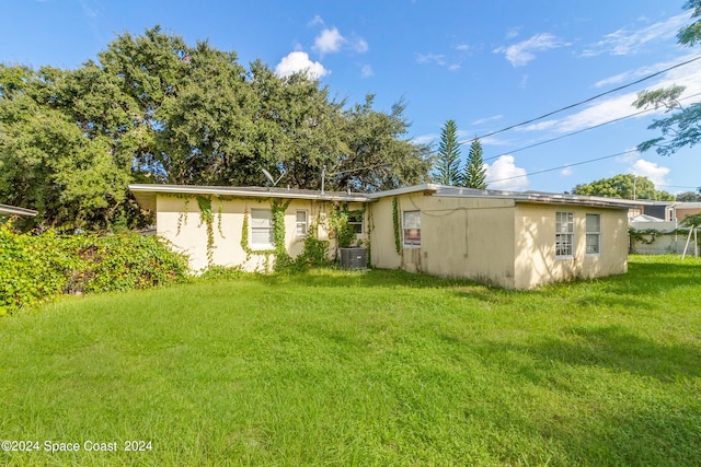 rear view of house featuring central AC and a lawn