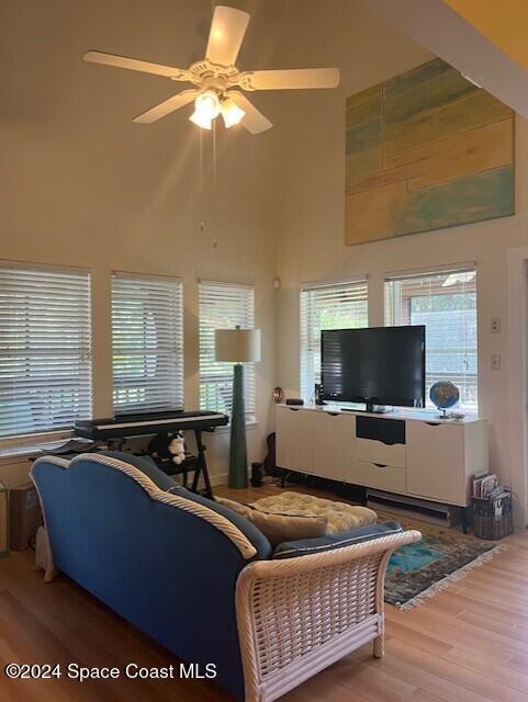 living room featuring wood-type flooring, a towering ceiling, and ceiling fan