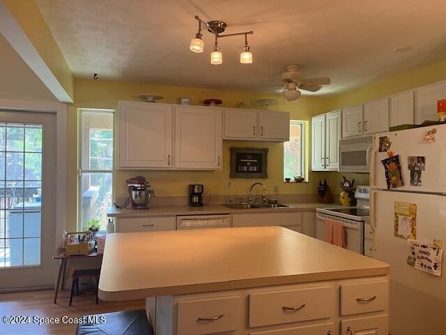 kitchen with white appliances, sink, ceiling fan, pendant lighting, and white cabinets