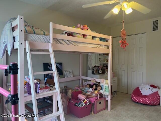 bedroom with a closet, ceiling fan, and light colored carpet