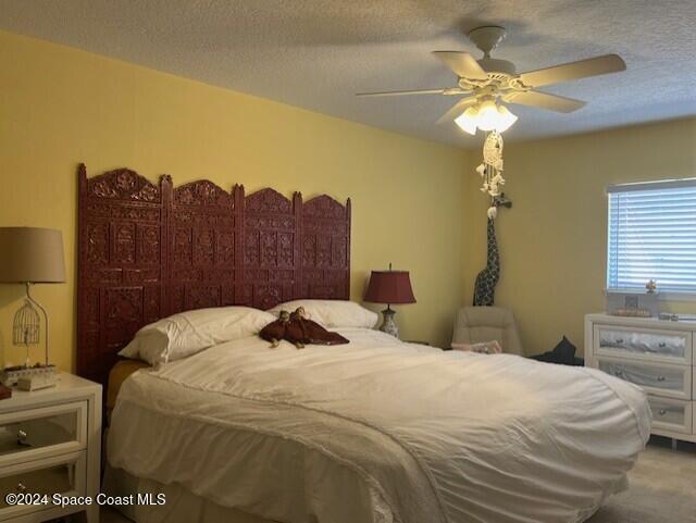 carpeted bedroom with a textured ceiling and ceiling fan