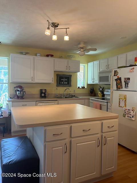 kitchen featuring white cabinets, a wealth of natural light, and white appliances