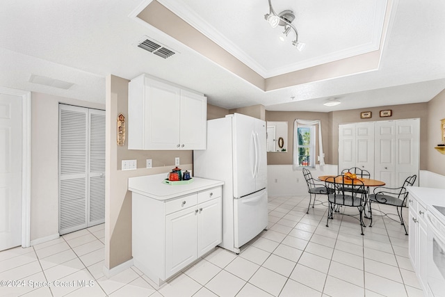 kitchen featuring white refrigerator, light tile patterned floors, a raised ceiling, white cabinets, and a textured ceiling