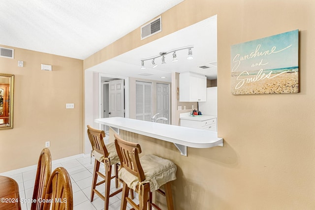 interior space featuring white cabinetry, light tile patterned floors, and a breakfast bar area