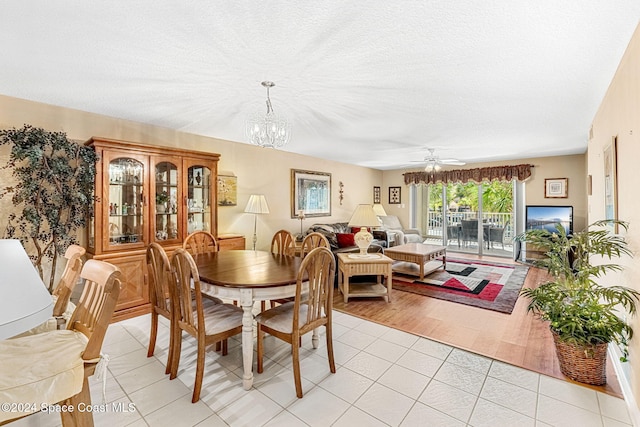 dining room featuring a textured ceiling, ceiling fan with notable chandelier, and light wood-type flooring