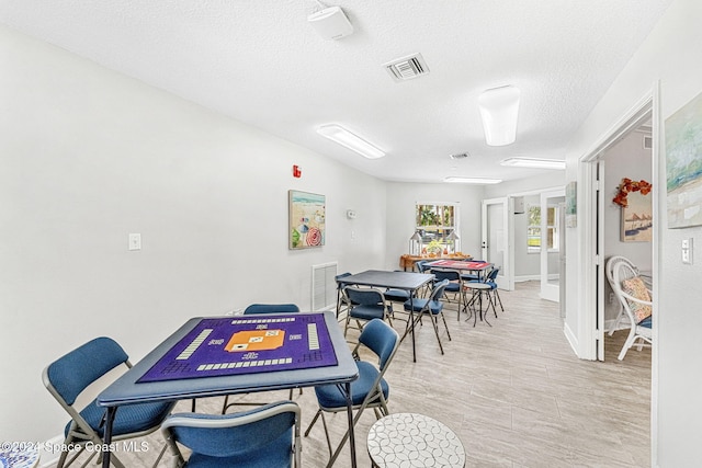 dining space with light hardwood / wood-style flooring and a textured ceiling