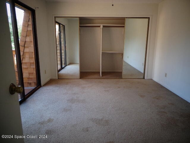 unfurnished bedroom with light carpet and a closet