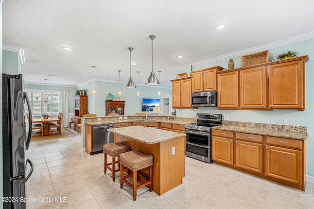 kitchen featuring appliances with stainless steel finishes, a center island, kitchen peninsula, hanging light fixtures, and ornamental molding