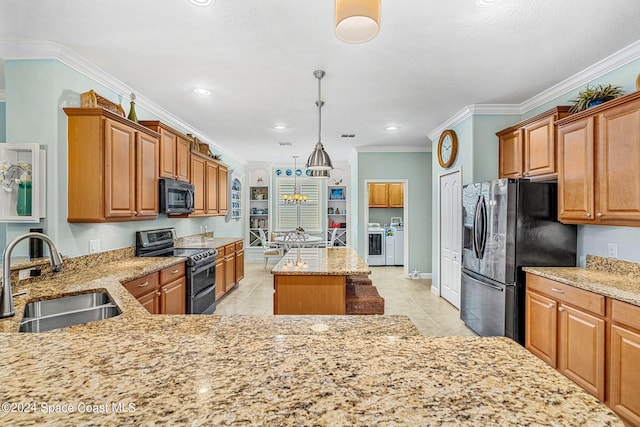 kitchen with washer and dryer, ornamental molding, black appliances, decorative light fixtures, and sink