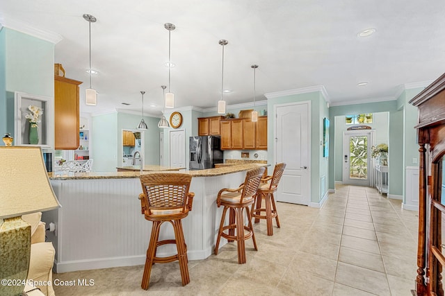 kitchen with ornamental molding, light stone counters, stainless steel fridge with ice dispenser, and kitchen peninsula