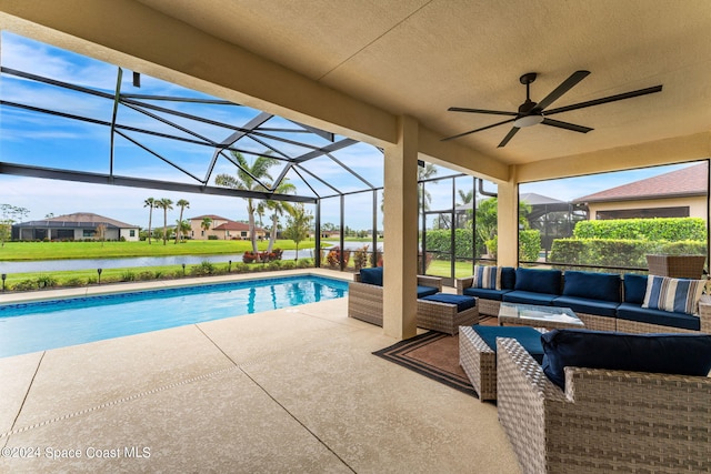 view of swimming pool featuring glass enclosure, a water view, an outdoor hangout area, ceiling fan, and a patio area