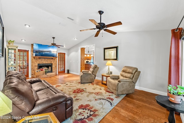 living room with lofted ceiling, hardwood / wood-style flooring, ceiling fan, and a brick fireplace