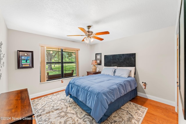 bedroom with ceiling fan, a textured ceiling, and light hardwood / wood-style flooring