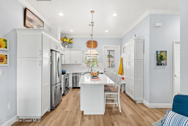 kitchen with a center island, appliances with stainless steel finishes, hanging light fixtures, and light wood-type flooring