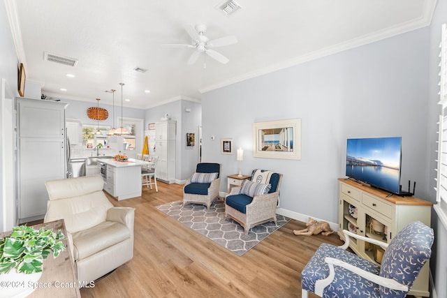 living room featuring ornamental molding, sink, light wood-type flooring, and ceiling fan