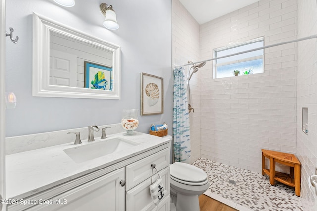 bathroom featuring vanity, toilet, tiled shower, and hardwood / wood-style floors