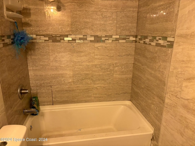 bathroom with tiled shower / bath and toilet