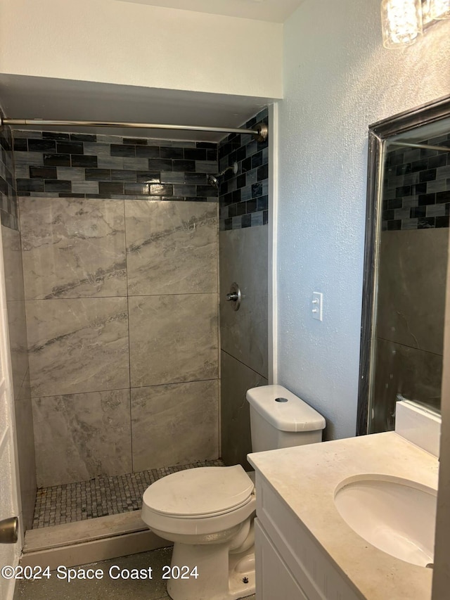 bathroom with a tile shower, vanity, and toilet