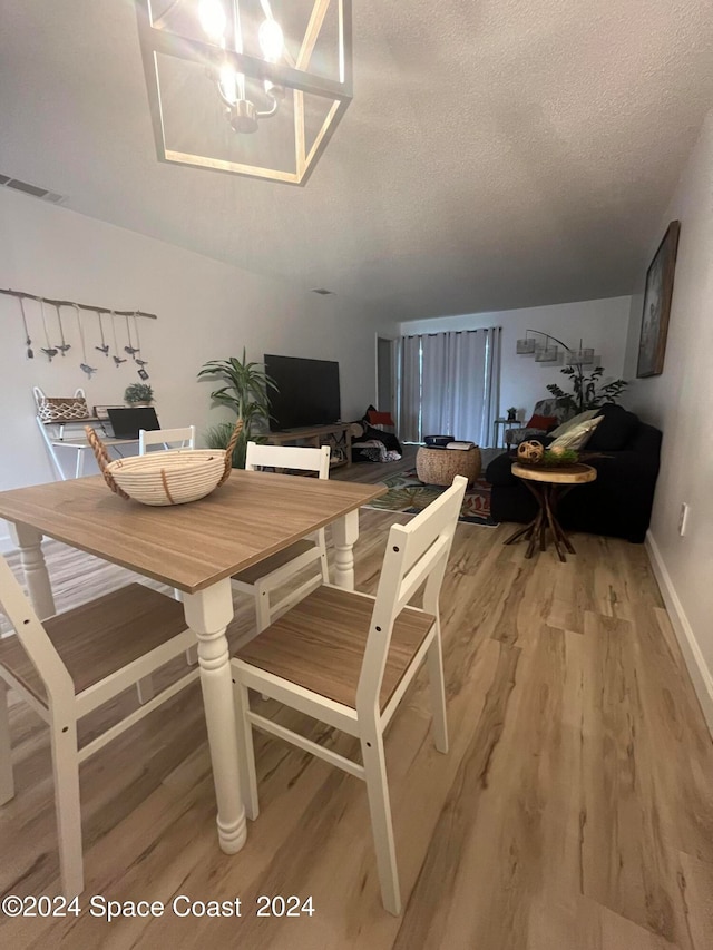 dining room with hardwood / wood-style floors, a notable chandelier, and a textured ceiling