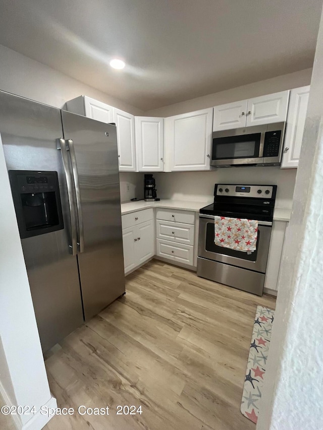 kitchen with white cabinets, appliances with stainless steel finishes, and light wood-type flooring